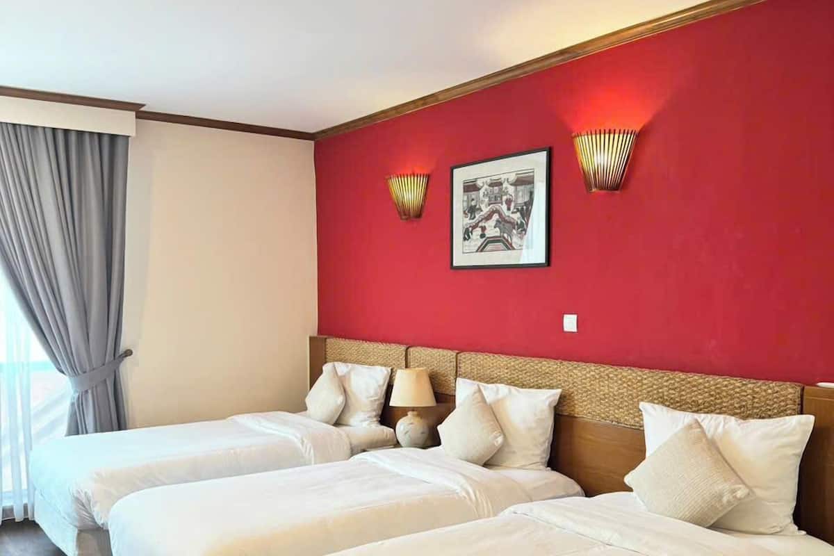 Una habitación de hotel con dos camas, una pared de acento roja y un cuadro enmarcado.
