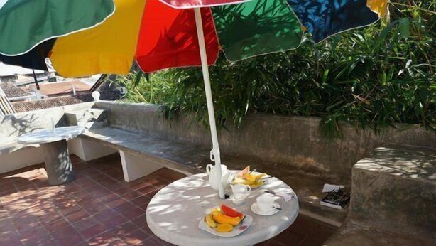 A round table with a white umbrella, a white teapot, and a plate of fruit. - Secret Palace House (Galle)