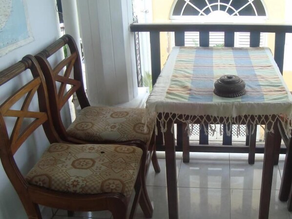 A dining area with a table and two chairs, a decorative tablecloth, and a window with a view.