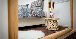 A cozy living room with a white sofa, patterned cushions, a small wooden side table with a vase of flowers, and a fluffy white rug. - Villa BBB (Oosterhout)