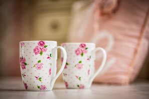 Two white ceramic cups with pink floral patterns and green leaves. - Villa BBB (Oosterhout)