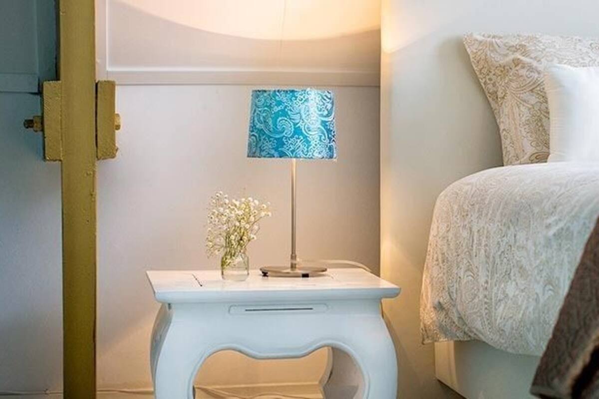 A bedroom with a bed, a bedside table with a lamp, and a wall-mounted artwork.