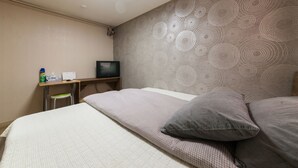 A hotel room with a bed, a desk with a computer, a chair, and a television. - YEHADOYE Guest House (Seoul)