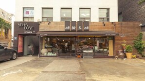 A storefront with a sign in a foreign language, a visible entrance, and a parking area in front. - YEHADOYE Guest House (Seoul)