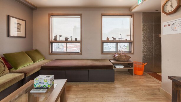 A modern living room with a sofa, a bench, a coffee table, and large windows. - YEHADOYE Guest House (Seoul)