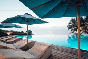 A poolside area with lounge chairs and umbrellas. - Suarga Padang Padang (Pecatu)