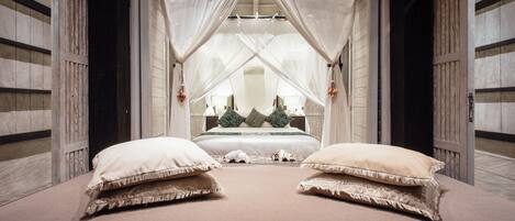 A bedroom with a canopy bed, two large pillows, and a nightstand with a lamp.