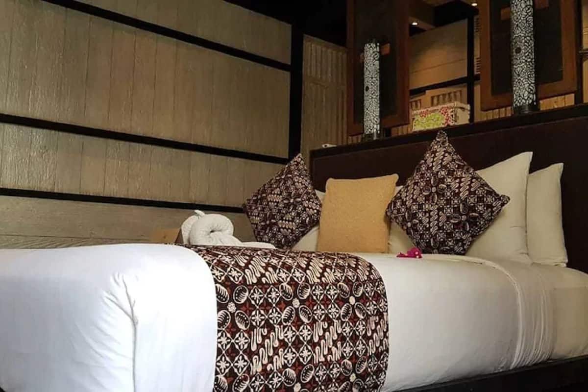 A neatly made bed with patterned bedding, a pillow, and a decorative item on the headboard.