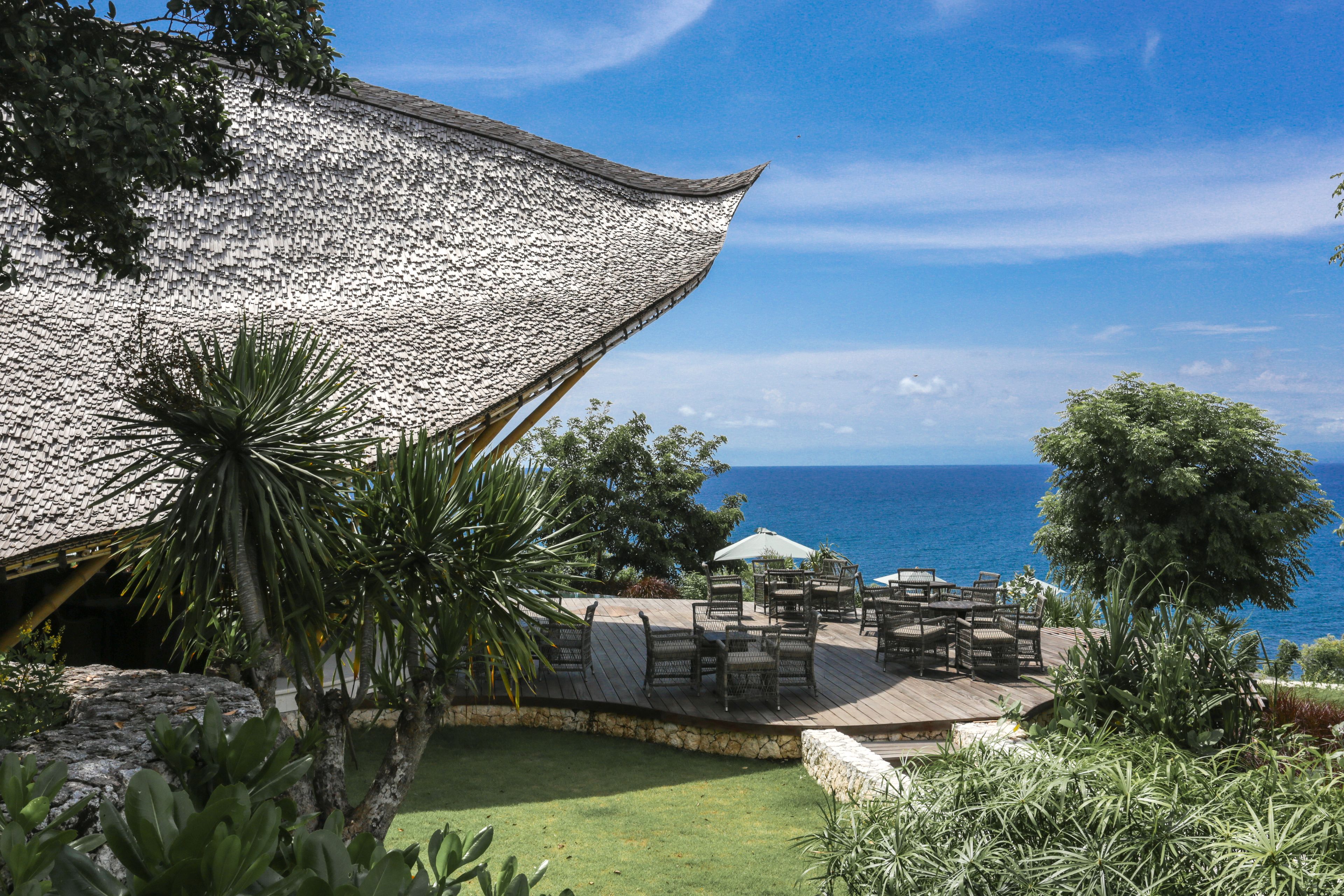 A patio with outdoor furniture overlooking the ocean.