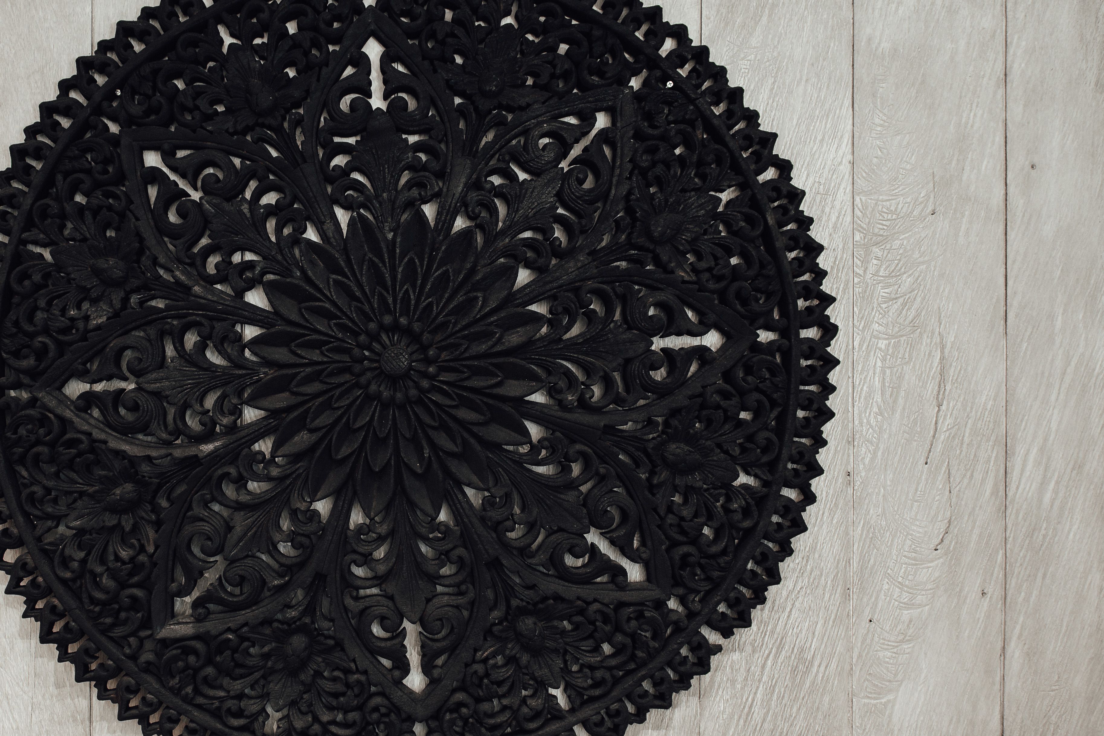 A circular black metal wall decor with intricate floral patterns.