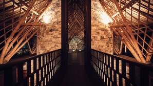 A corridor with bamboo beams and brick walls, leading to a bright area at the end. - Suarga Padang Padang (Pecatu)