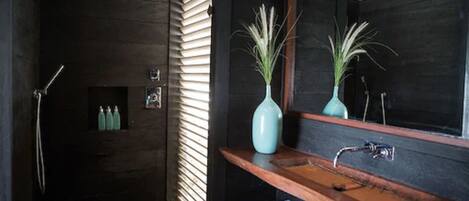 A modern bathroom with a dark wood vanity, a large mirror, and a shower area.
