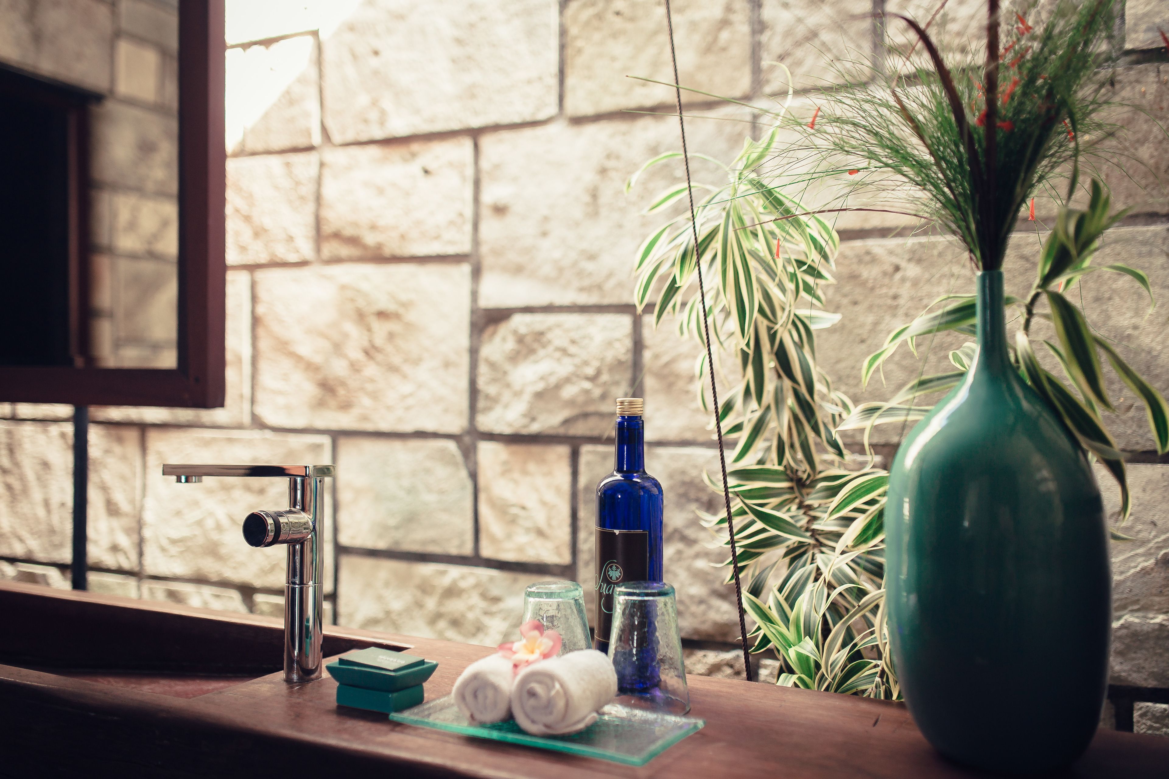 A bathroom counter with a towel rack, a bottle, and a vase.