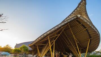 A modern building with a unique conical roof structure, outdoor seating area, and a pathway leading to the entrance.