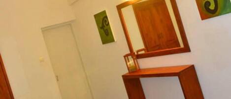 A room with a bed, a desk, a mirror, and a TV on the wall.