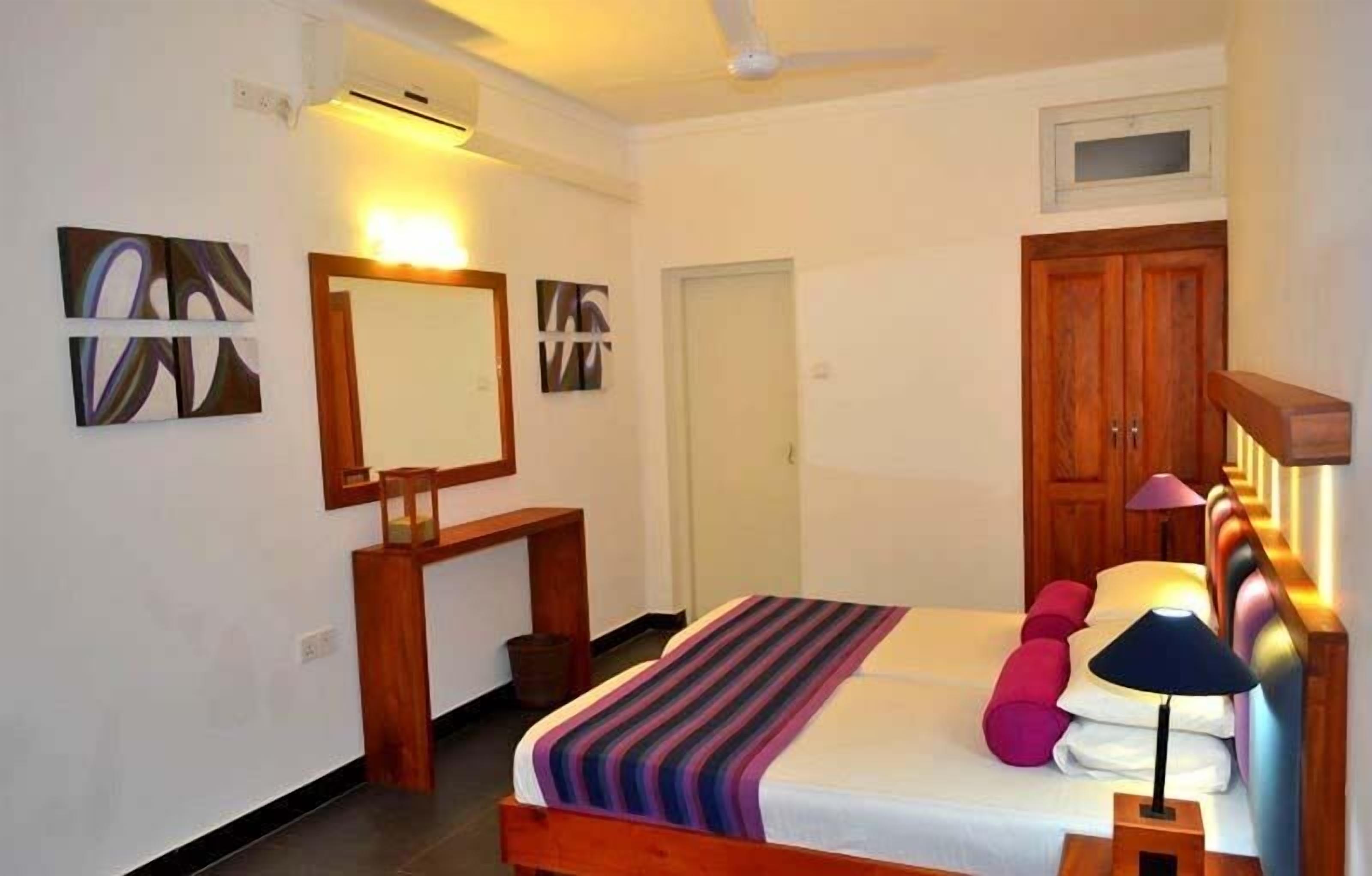 A bedroom with a bed, bedside lamp, and a wooden wardrobe.