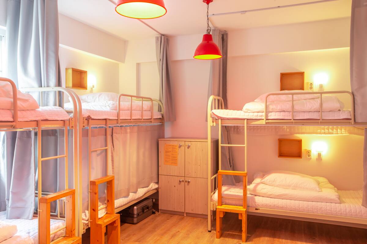 A dormitory room with bunk beds, a wardrobe, and a desk.