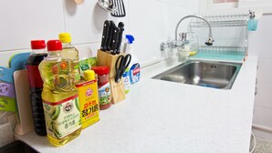 A kitchen counter with various condiments, a knife block, and a hanging utensil rack.