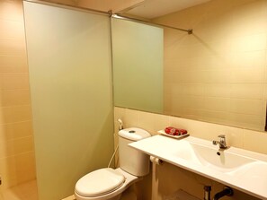 A bathroom with a toilet, sink, and mirror. - Ameera Hotel (Pekanbaru)