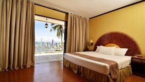 Une chambre d’hôtel avec un grand lit, une tête de lit en bois, une table de chevet et une vue sur la plage.