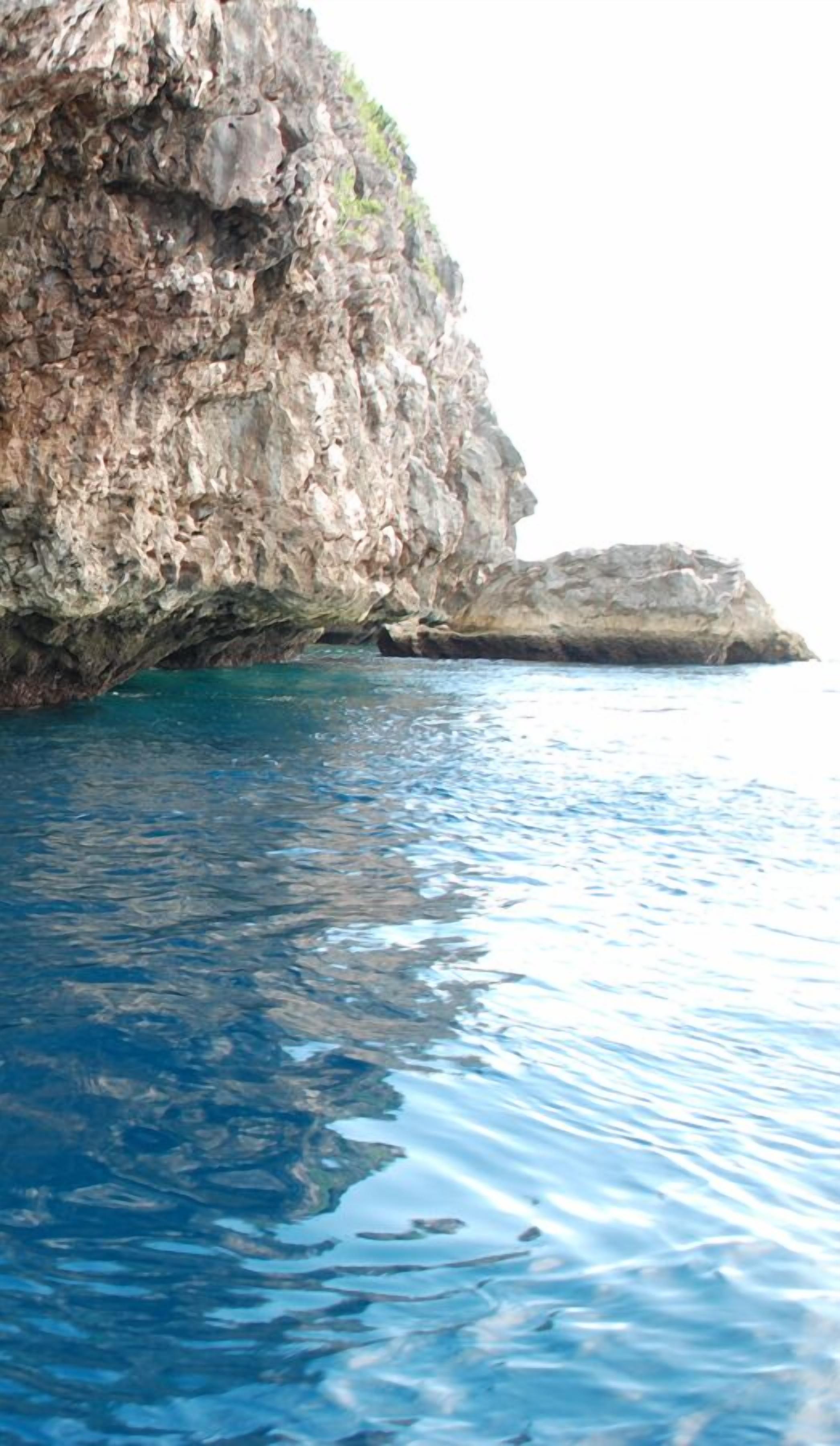 A coastal scene with clear blue water and rocky cliffs.