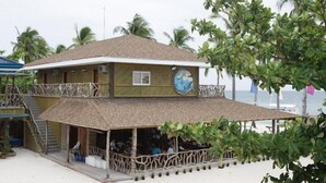 Un bâtiment à deux étages doté d’un balcon et d’un espace extérieur aménagé avec des sièges.
