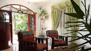 Un salon chaleureux avec deux fauteuils à motifs écossais, une table basse en bois et une bibliothèque.