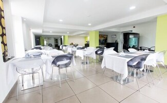 A spacious dining area with multiple tables and chairs, a television, and a tiled floor.