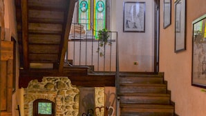 Una escalera conduce a un segundo piso con un muro de piedra y un ventanal pequeño.