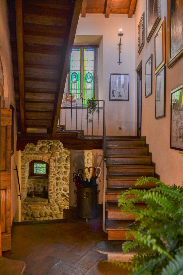 A staircase leading to a second floor with a stone wall and a small window.