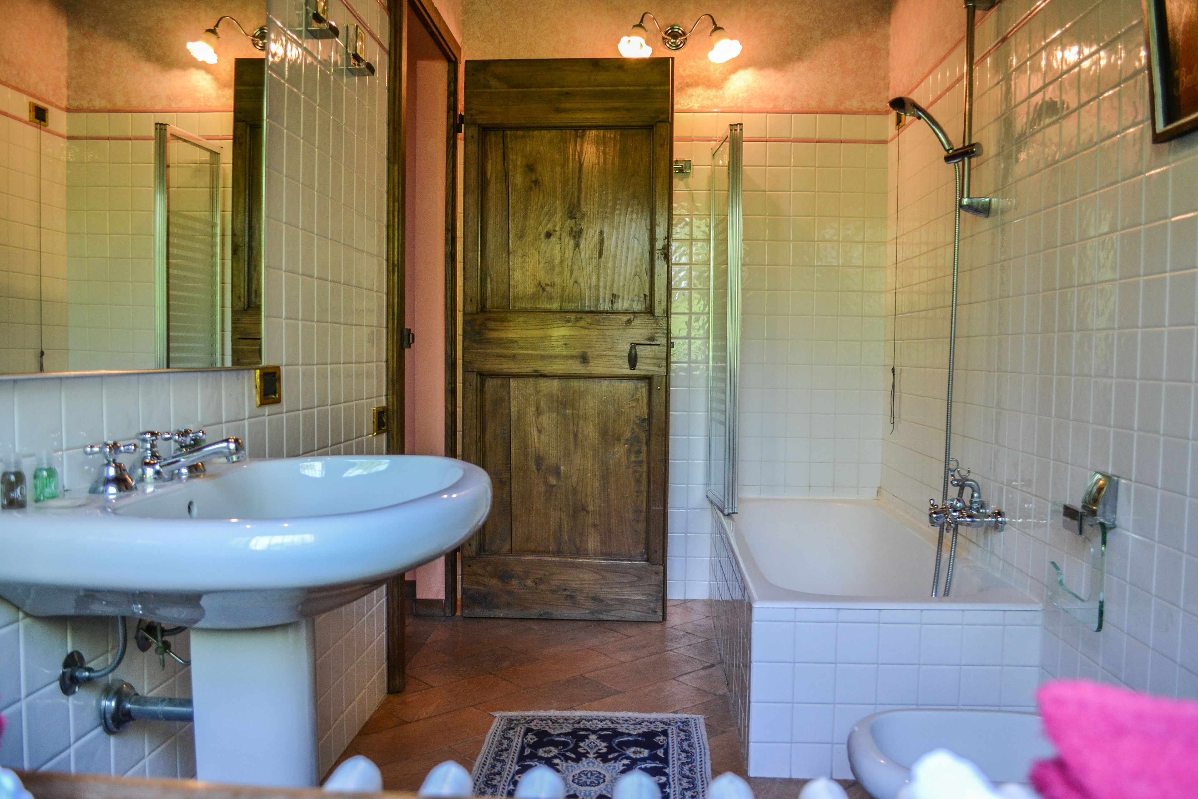 A bathroom with a wooden door, a sink, a bathtub, and a shower.