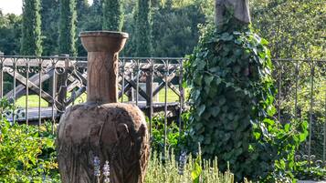 Un giardino con un'ampia vaso e una statua.
