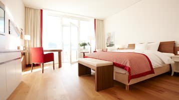 A hotel room with a bed, a desk, a chair, and a bench.