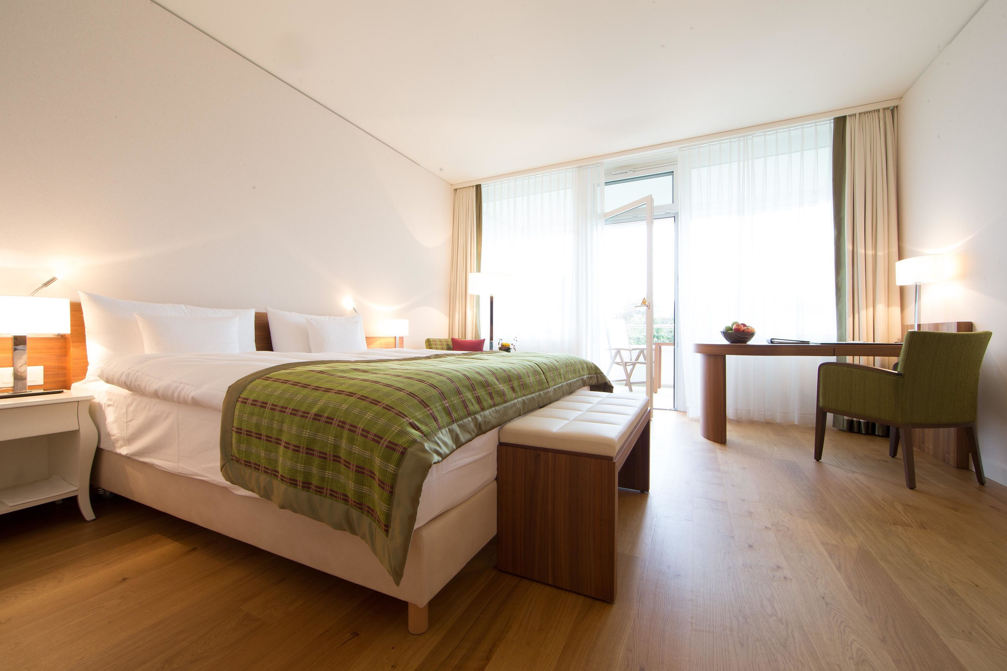 Une chambre d’hôtel avec un lit, un bureau, une chaise et un banc.