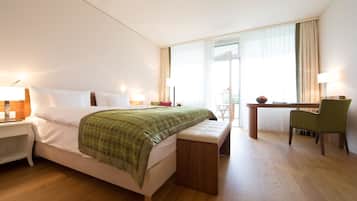 Une chambre d’hôtel avec un lit, un bureau, une chaise et un banc.