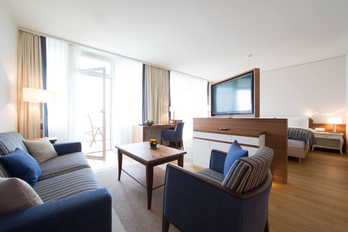 Une chambre d’hôtel moderne équipée d’un canapé, d’une table à manger, d’un téléviseur et d’un bureau.