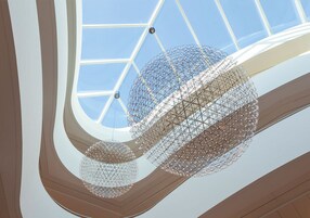 Un diseño arquitectónico moderno con techo de cristal y lámparas geométricas.