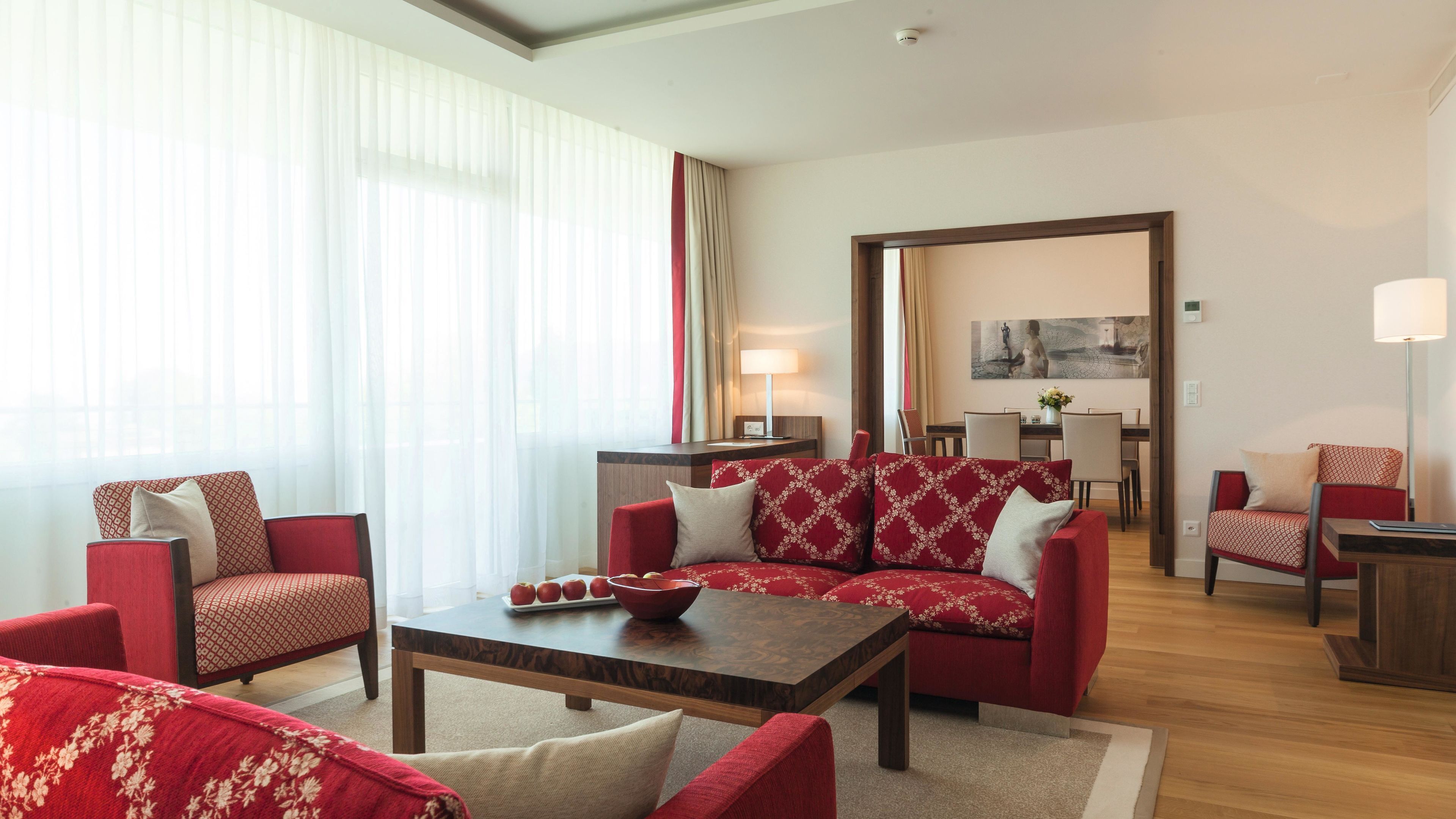Ein modernes Wohnzimmer mit roter Polstermöbeln, einem Holztisch und einem Essbereich mit Tisch und Stühlen.