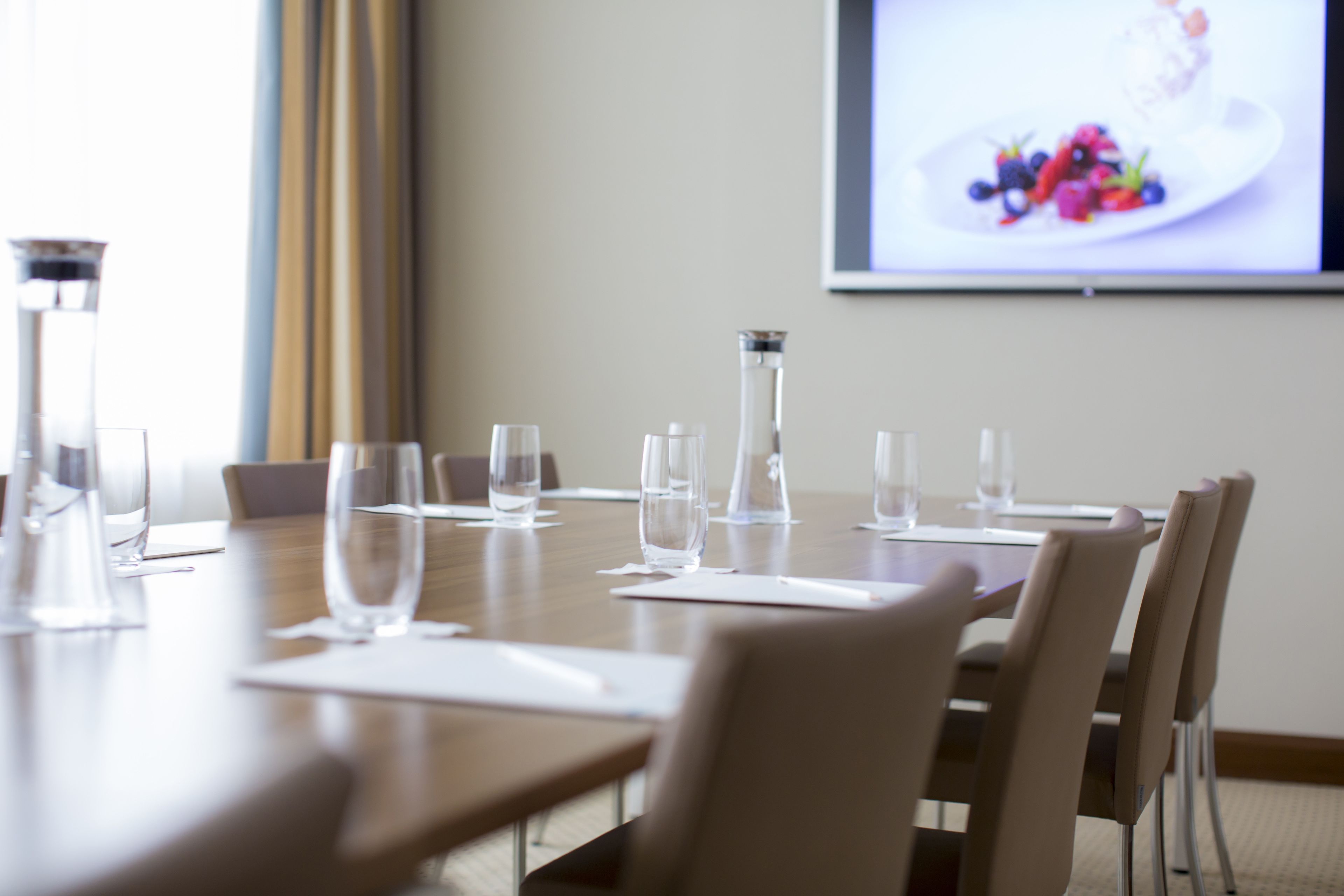 A conference room with a long table, chairs, and water glasses.