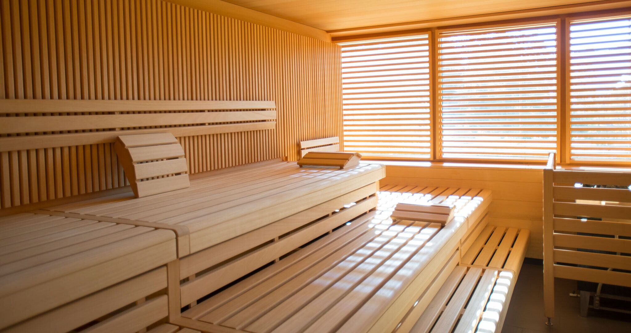 Una habitación con una pared de listones de madera, una cama con cabecera y una ventana con persianas horizontales.