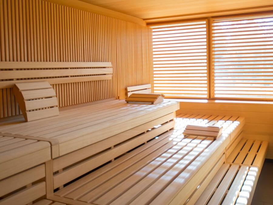 Una habitación con una pared de listones de madera, una cama con cabecera y una ventana con persianas horizontales.