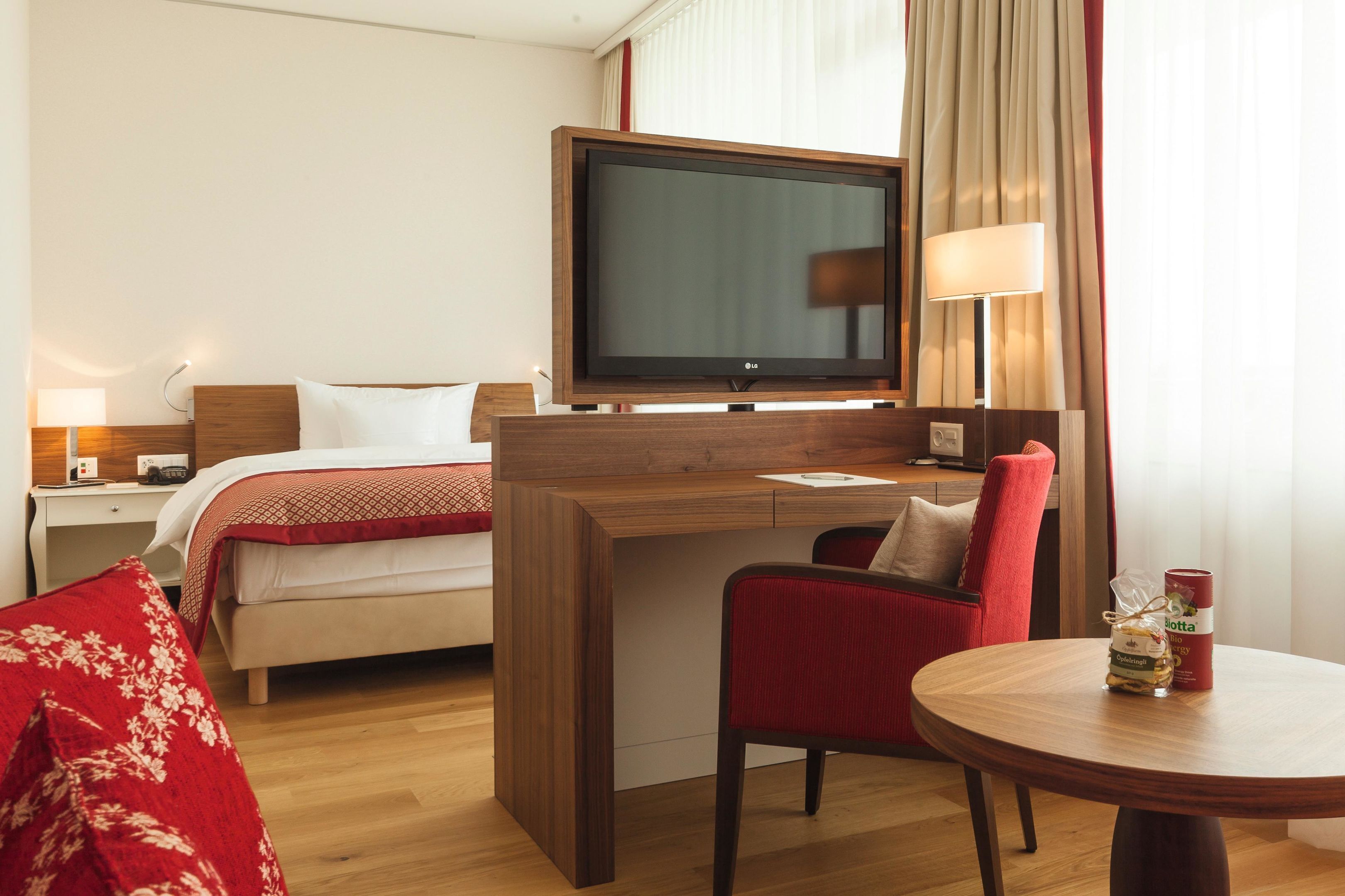 Una habitación de hotel con cama, escritorio con televisor, silla y mesa.
