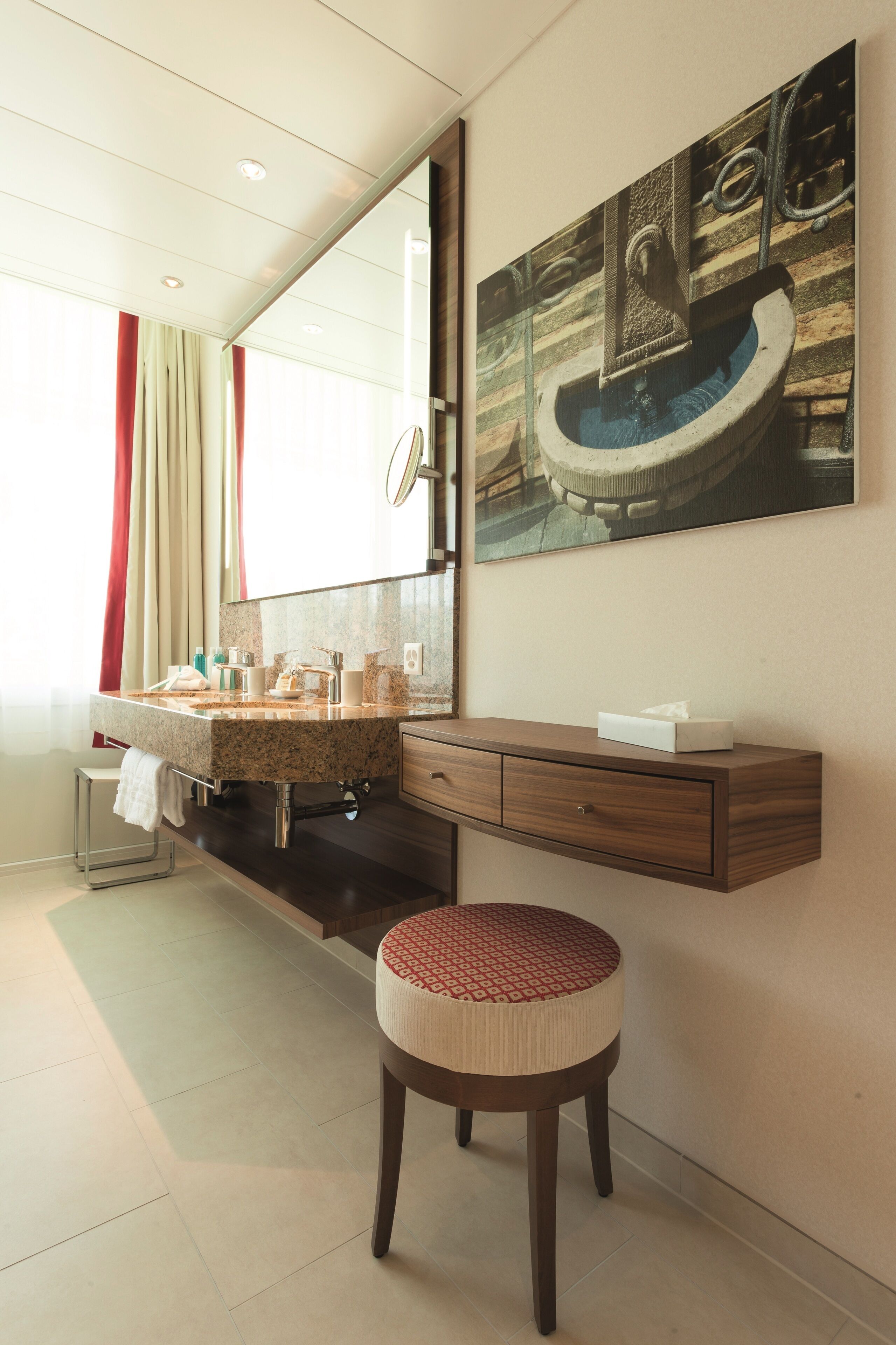Un baño moderno con un espejo grande, un lavabo con una toalla y un taburete.