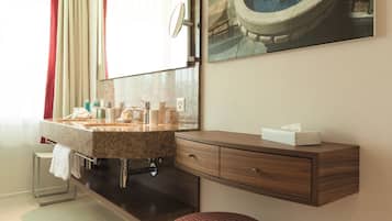 Un baño moderno con un espejo grande, un lavabo con una toalla y un taburete.