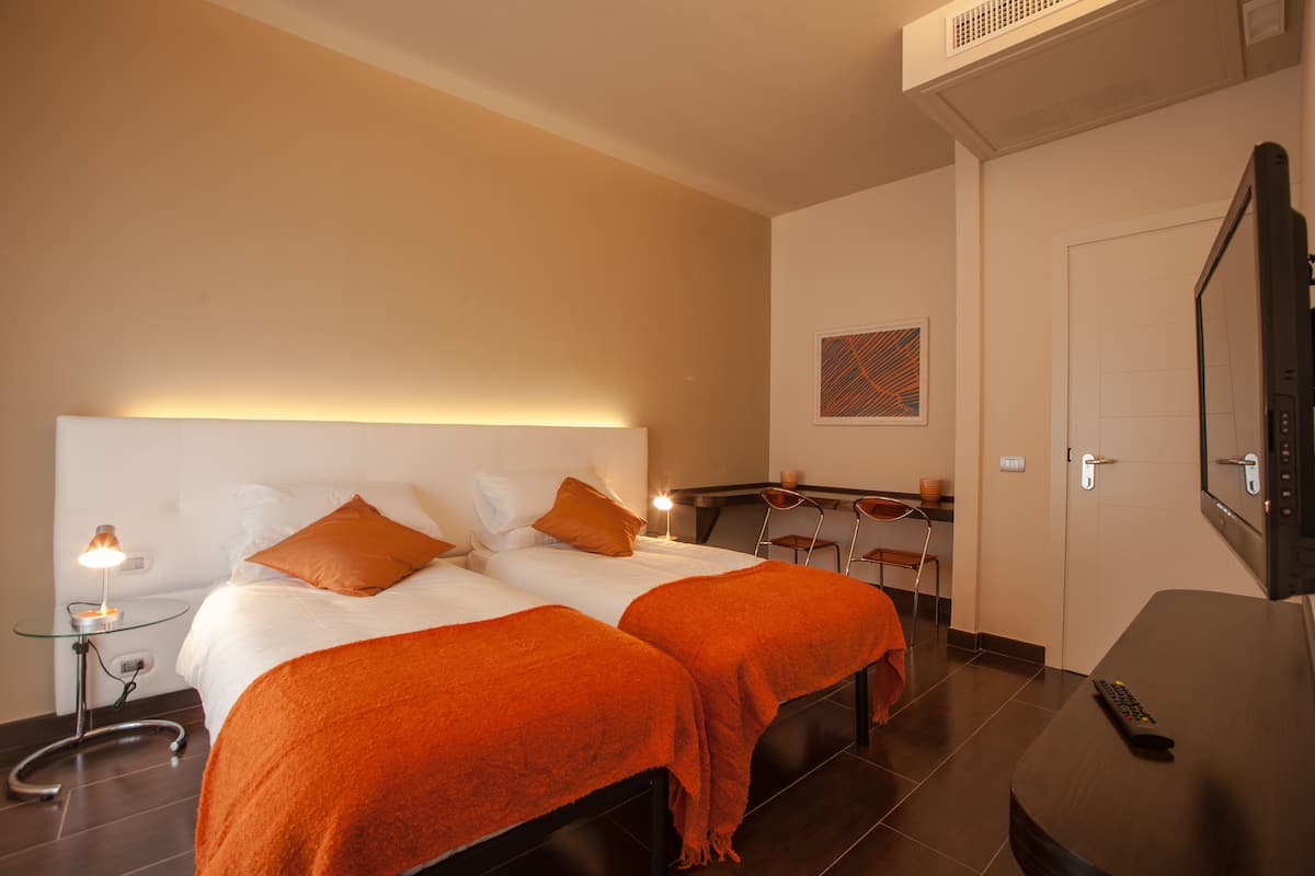 A hotel room with two beds, a TV, a desk, and a chair.