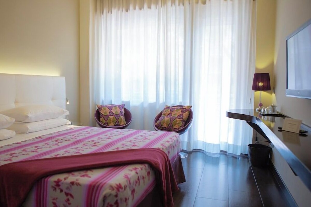 Une chambre d’hôtel avec un lit, deux chaises, un bureau et un téléviseur.