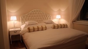 A neatly made bed with a tufted headboard, two bedside tables with lamps, and a window with curtains. - Banica Apartments & Rooms (Split)