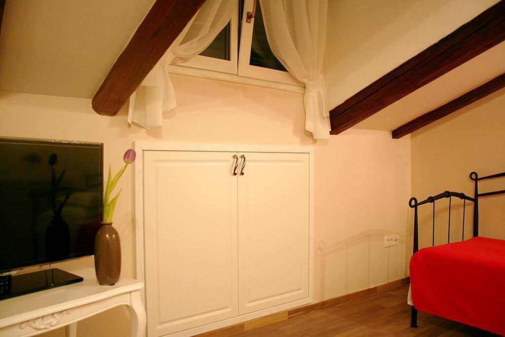 Ein Schlafzimmer mit Bett, Kleiderschrank, Fernseher und einer Vase mit Blumen.