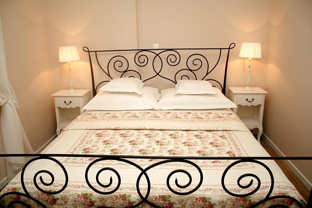 A neatly made bed with floral bedding, two bedside tables with lamps, and a decorative metal headboard.