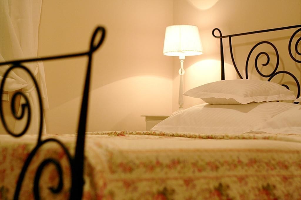 A bed with a floral bedspread, a white pillow, and a nightstand with a lamp.